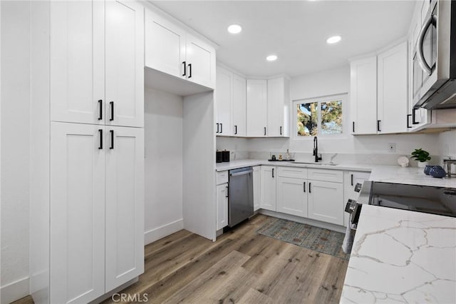 kitchen with light stone countertops, sink, white cabinetry, and appliances with stainless steel finishes