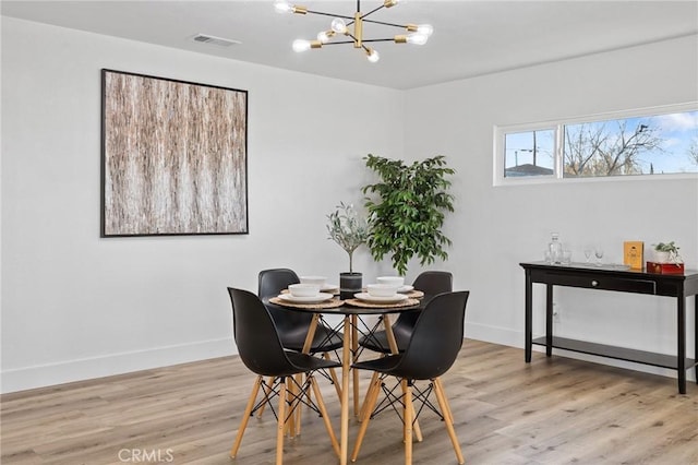 dining area with light hardwood / wood-style flooring and a notable chandelier