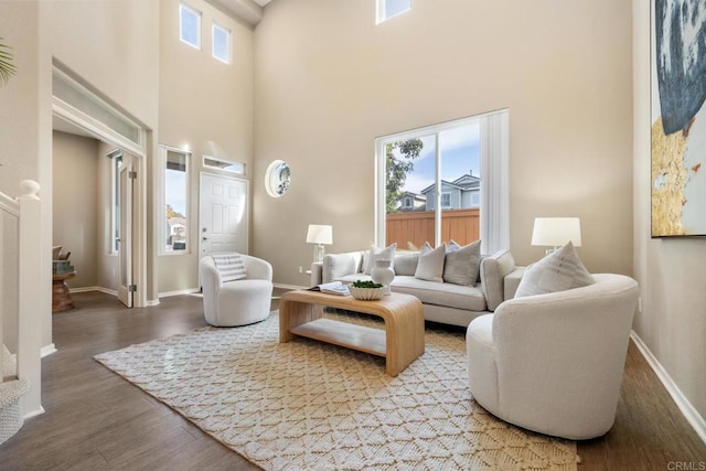 living room with wood-type flooring and a towering ceiling