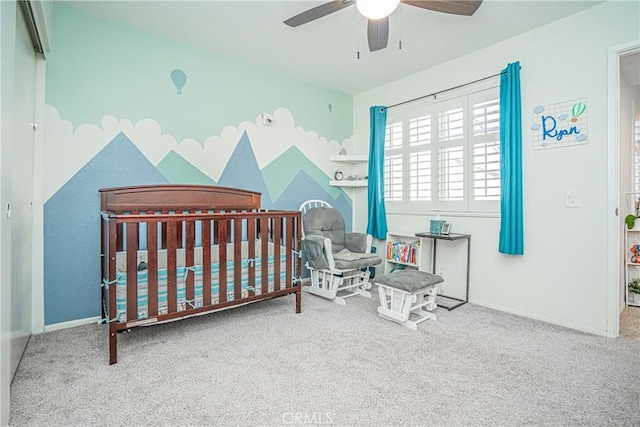 carpeted bedroom featuring ceiling fan and a crib