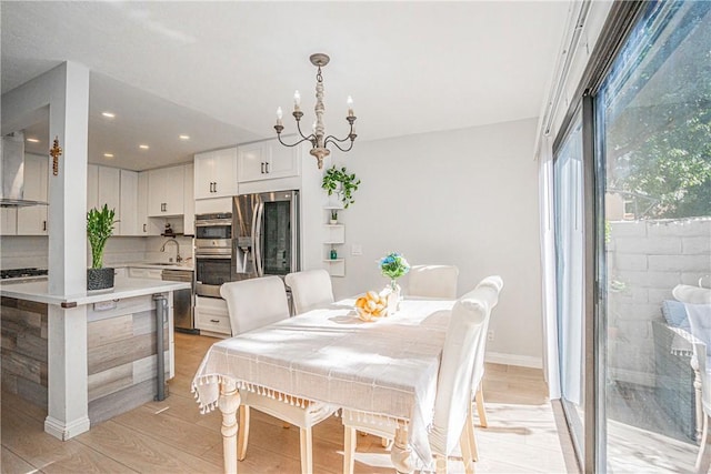 dining space featuring sink, a chandelier, and light hardwood / wood-style flooring