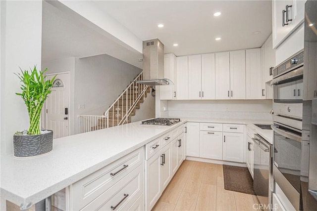 kitchen with stainless steel appliances, white cabinetry, light hardwood / wood-style floors, and island range hood