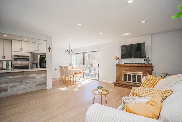 living room featuring light hardwood / wood-style flooring, a notable chandelier, and a fireplace