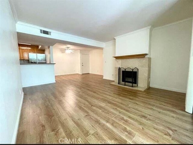 unfurnished living room featuring ceiling fan, ornamental molding, and hardwood / wood-style flooring