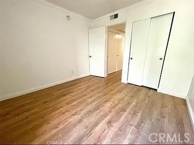 unfurnished bedroom with a closet, ornamental molding, and hardwood / wood-style flooring