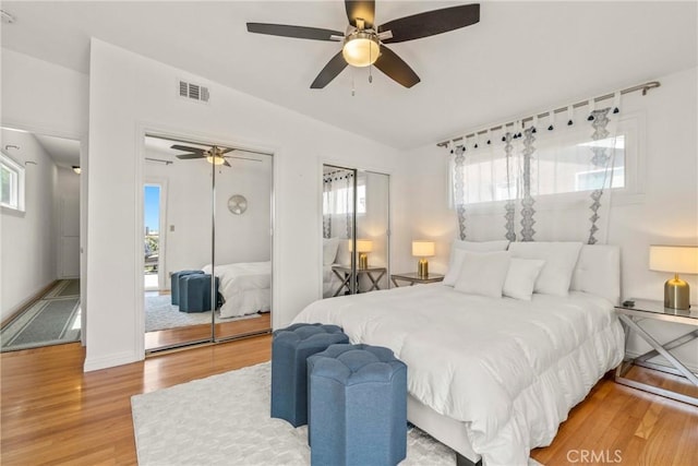 bedroom featuring ceiling fan, lofted ceiling, hardwood / wood-style floors, and two closets