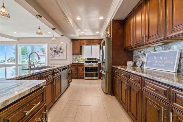 kitchen featuring sink, appliances with stainless steel finishes, tasteful backsplash, a tray ceiling, and decorative light fixtures