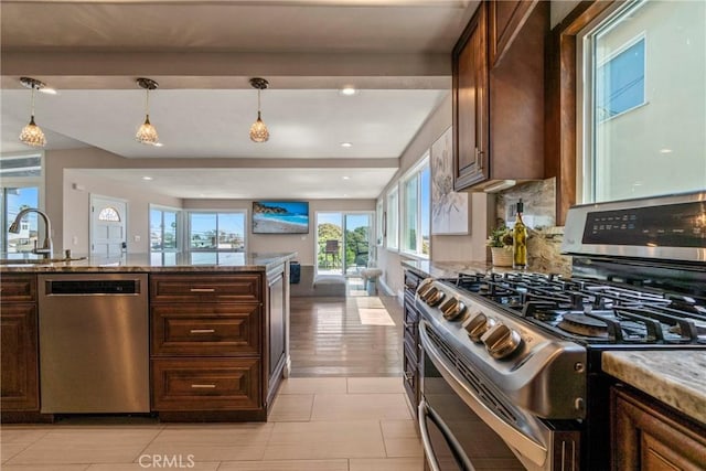 kitchen featuring sink, light stone countertops, hanging light fixtures, and appliances with stainless steel finishes