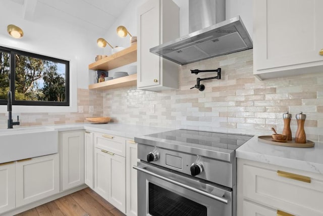 kitchen featuring white cabinetry, decorative backsplash, stainless steel range with electric stovetop, and wall chimney exhaust hood