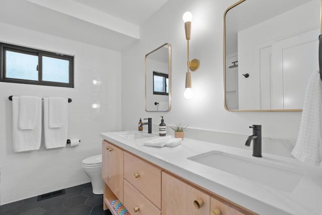 bathroom with tile patterned flooring, vanity, toilet, and a healthy amount of sunlight