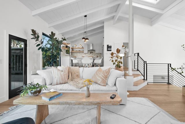 living room featuring beamed ceiling, a skylight, high vaulted ceiling, and light hardwood / wood-style flooring