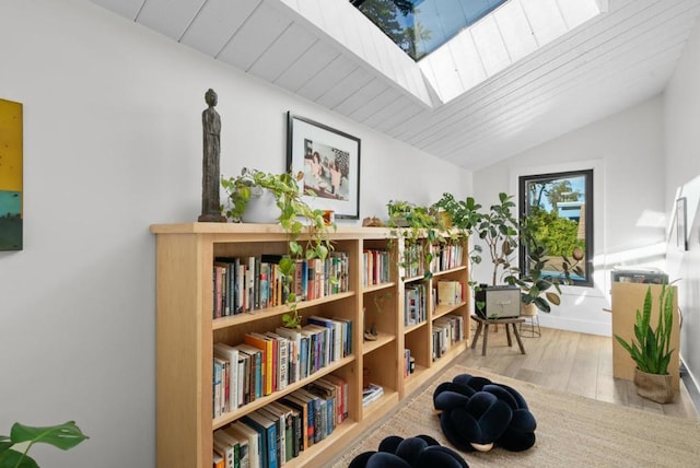 sitting room featuring wooden ceiling, vaulted ceiling with skylight, and light wood-type flooring