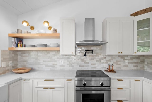 kitchen featuring white cabinets, wall chimney range hood, high end stainless steel range, and decorative backsplash