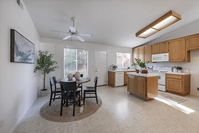 kitchen featuring a kitchen island, a wealth of natural light, lofted ceiling, and white appliances