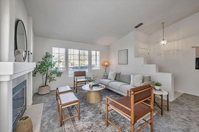 carpeted living room with a tiled fireplace and vaulted ceiling