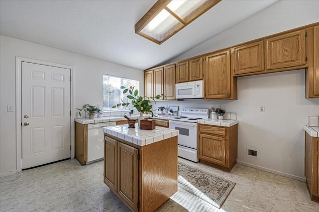 kitchen with white appliances, lofted ceiling, tile counters, and a center island