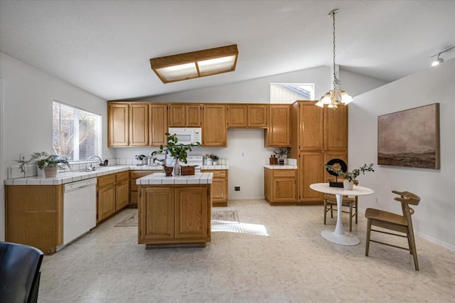 kitchen featuring sink, tile counters, a kitchen island, pendant lighting, and white appliances