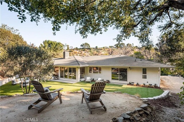 back of property featuring a lawn, a patio, and a chimney