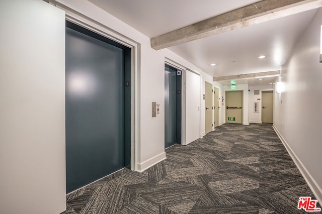 hallway featuring elevator, beamed ceiling, and dark colored carpet