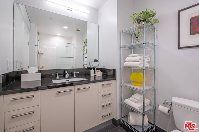 bathroom with toilet, an enclosed shower, and vanity