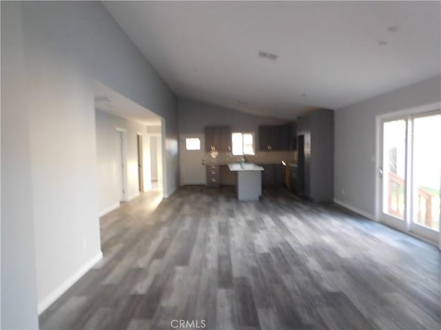 unfurnished living room with dark wood-type flooring and vaulted ceiling