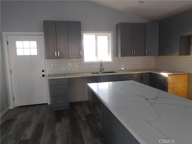 kitchen with dark wood-type flooring, sink, backsplash, vaulted ceiling, and gray cabinetry