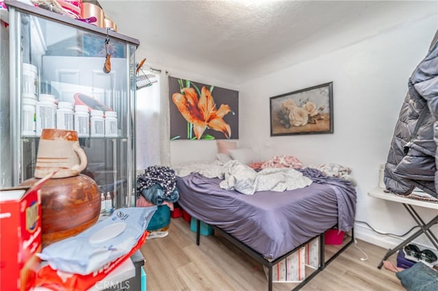 bedroom with light wood-type flooring and a textured ceiling