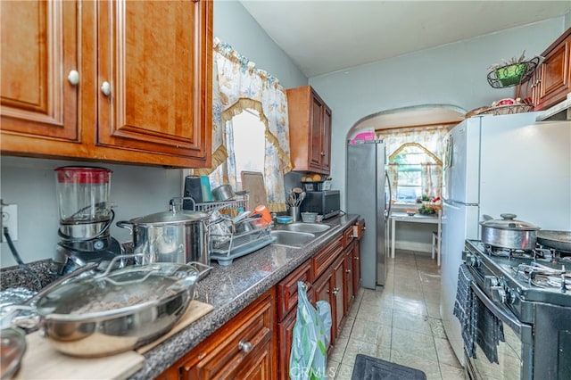 kitchen with sink, appliances with stainless steel finishes, and dark stone counters