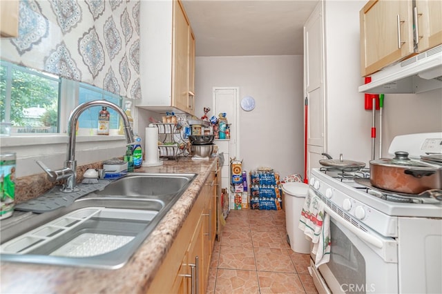 kitchen featuring light tile patterned flooring, white gas stove, light brown cabinetry, and sink