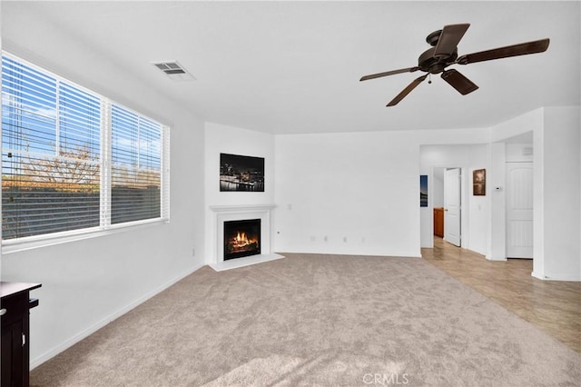 unfurnished living room with ceiling fan and light colored carpet