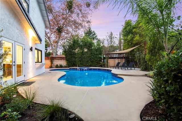 pool at dusk featuring a patio