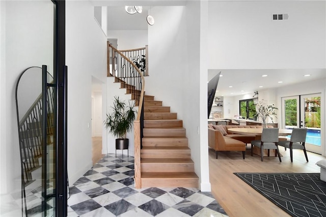 stairs with hardwood / wood-style flooring and french doors