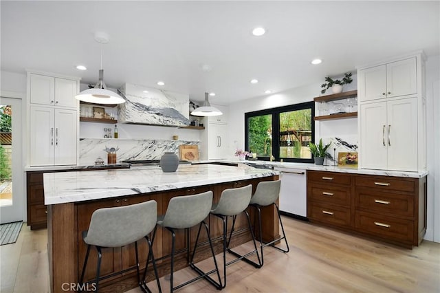 kitchen featuring custom exhaust hood, white cabinets, hanging light fixtures, and white dishwasher