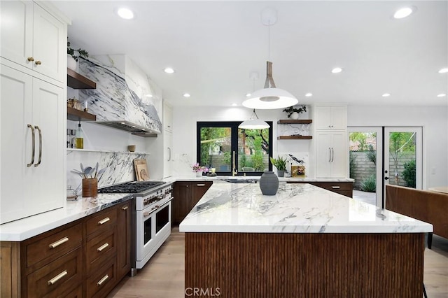 kitchen with double oven range, white cabinetry, and hanging light fixtures