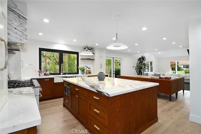 kitchen featuring decorative light fixtures, appliances with stainless steel finishes, light stone counters, and a center island