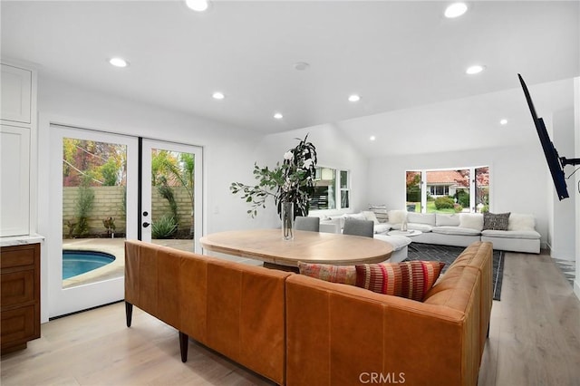 living room with light wood-type flooring, a wealth of natural light, and vaulted ceiling