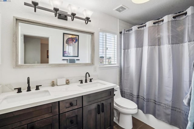 full bathroom featuring toilet, a textured ceiling, vanity, and shower / tub combo with curtain