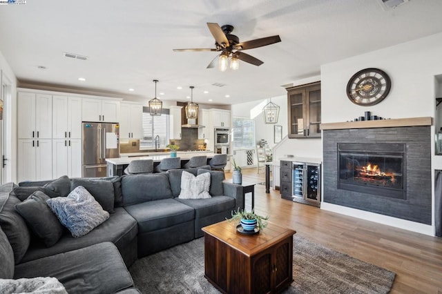 living room with wine cooler, ceiling fan, dark wood-type flooring, and sink