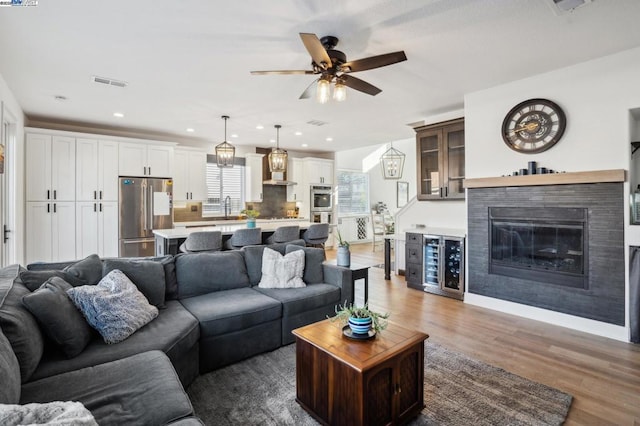 living room with dark wood-type flooring, sink, beverage cooler, and ceiling fan