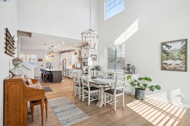 dining room featuring plenty of natural light, sink, a towering ceiling, and light wood-type flooring