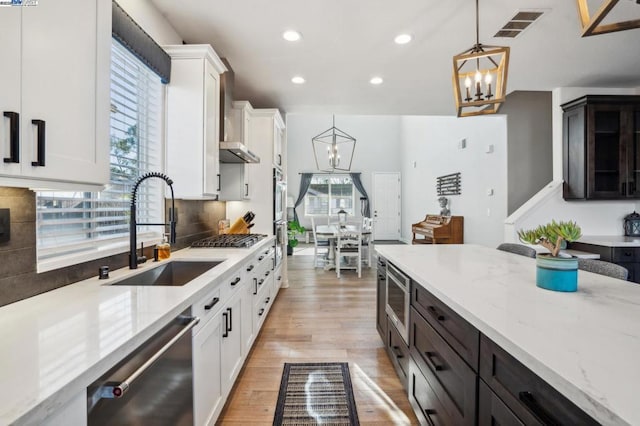 kitchen featuring appliances with stainless steel finishes, an inviting chandelier, sink, hanging light fixtures, and dark brown cabinets