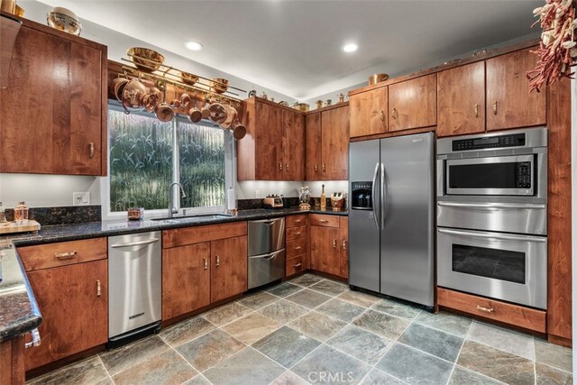 kitchen featuring sink, appliances with stainless steel finishes, and dark stone counters