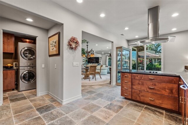 kitchen with stacked washer and dryer, island range hood, and black electric cooktop