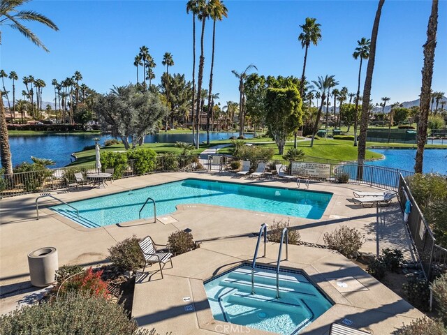 view of pool featuring a water view, a patio area, and a community hot tub