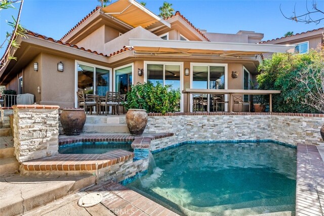 back of property with a pool with hot tub, a patio area, and pool water feature