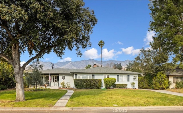 ranch-style home featuring a mountain view and a front lawn