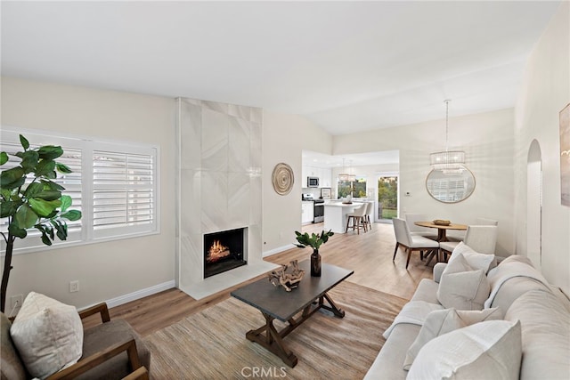 living room featuring a premium fireplace, lofted ceiling, and light hardwood / wood-style floors