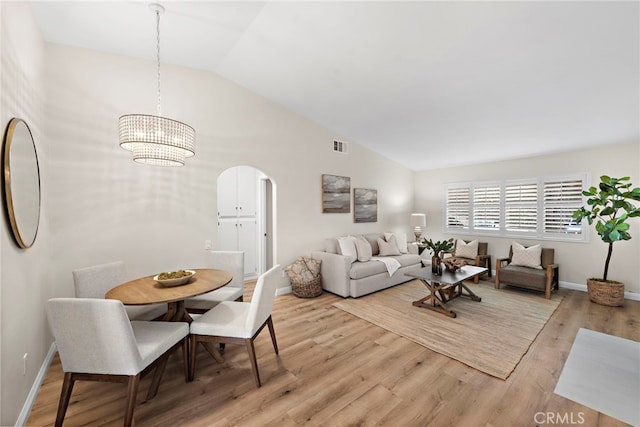 living room featuring lofted ceiling, a chandelier, and light wood-type flooring