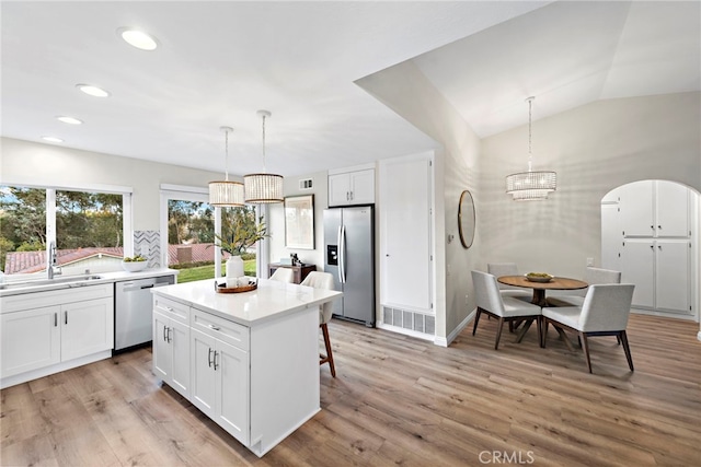 kitchen with stainless steel appliances, hanging light fixtures, a kitchen island, white cabinets, and sink