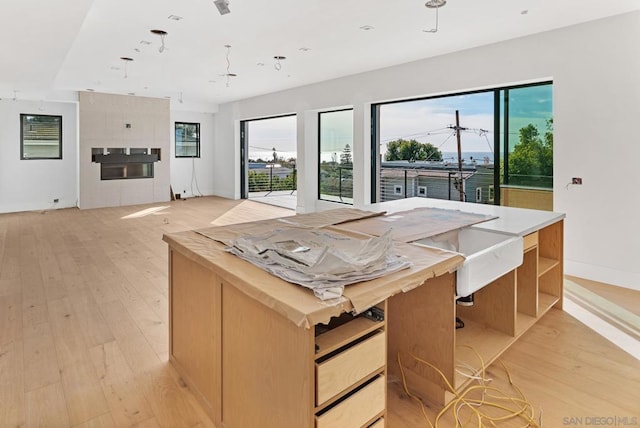 kitchen featuring a healthy amount of sunlight, a center island, light hardwood / wood-style flooring, and light brown cabinets